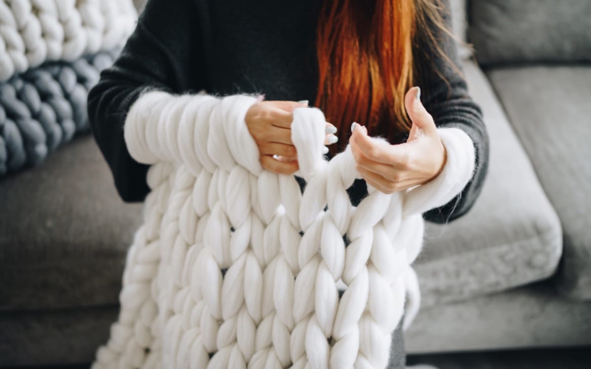 arm knitting of chunky knit blanket from white merino wool